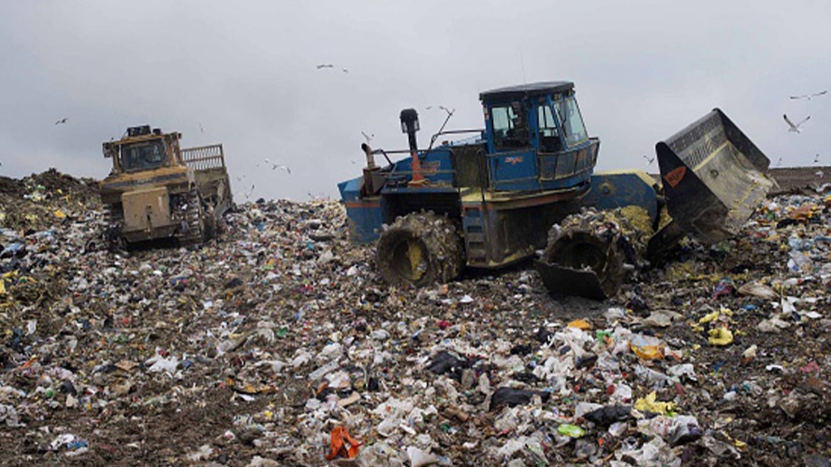 A bull dozer, left, spreads trash as a compactor packs it down to be covered with fresh dirt at the Defiance County Landfill in Defiance, Ohio, 