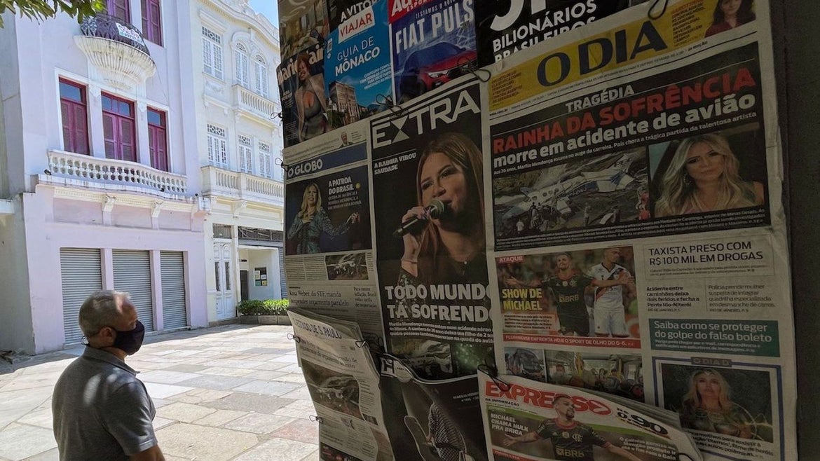 A woman walks by a news stand displaying Brazilian newspapers with the news of the death of Brazilian singer Marilia Mendonca on frontpage, in Rio de Janeiro, Brazil, on November 6, 2021.