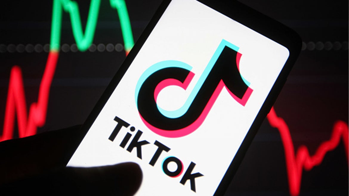 TikTok logo is seen on a smartphone in a hand. 
