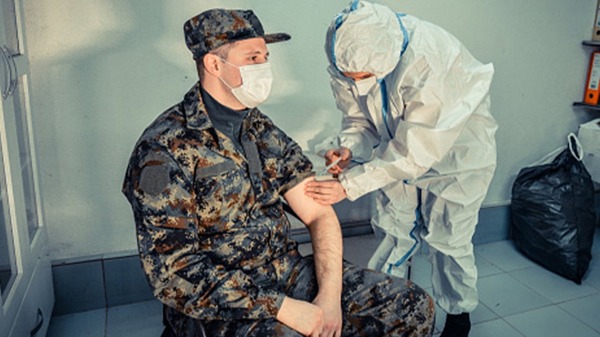 Army soldier gets vaccinated by a doctor.
