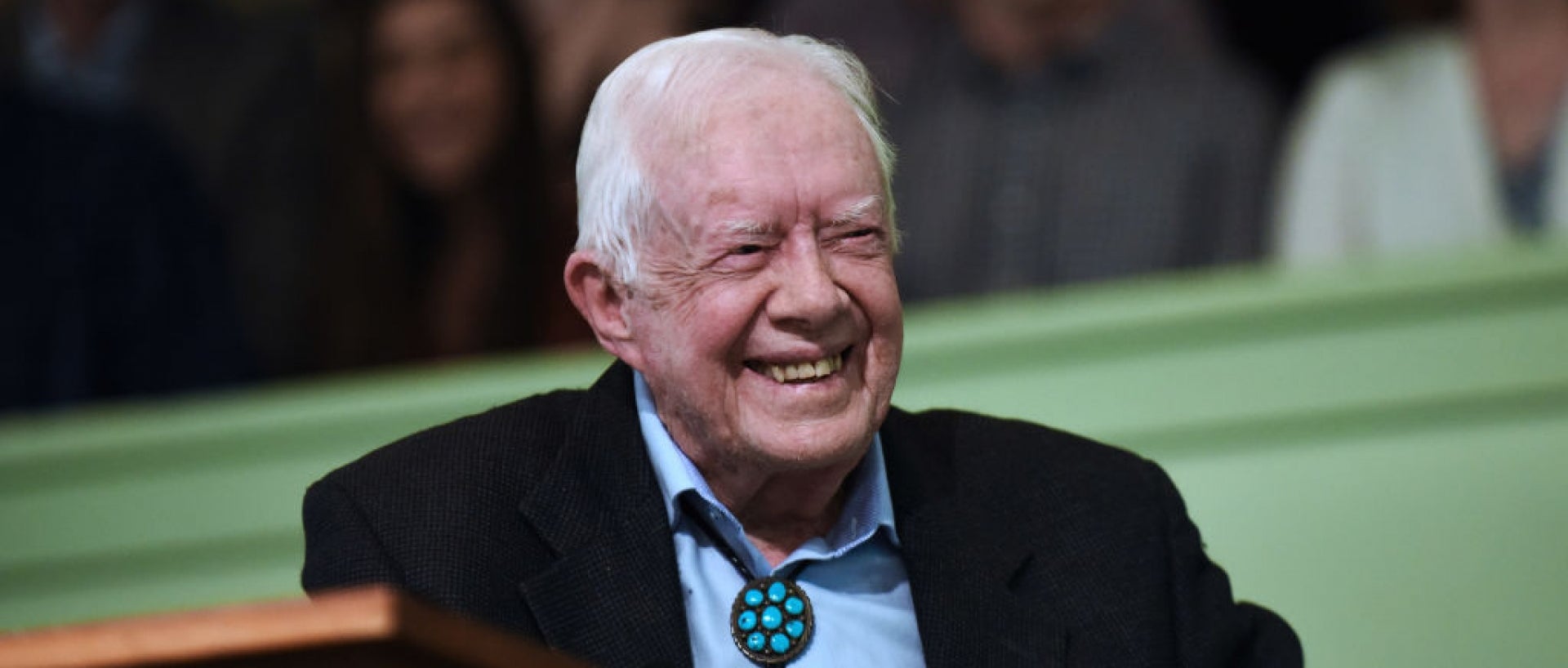 Jimmy Carter smiling sitting at podium