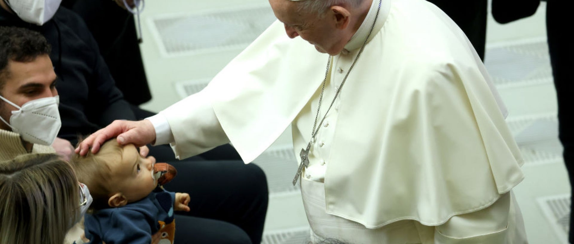 Pope Francis petting a child's head in a crowd