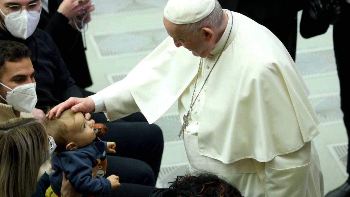 Pope Francis petting a child's head in a crowd