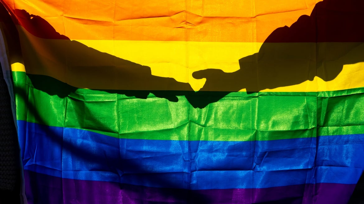 LGBTQ Pride flag with shadow of hands behind
