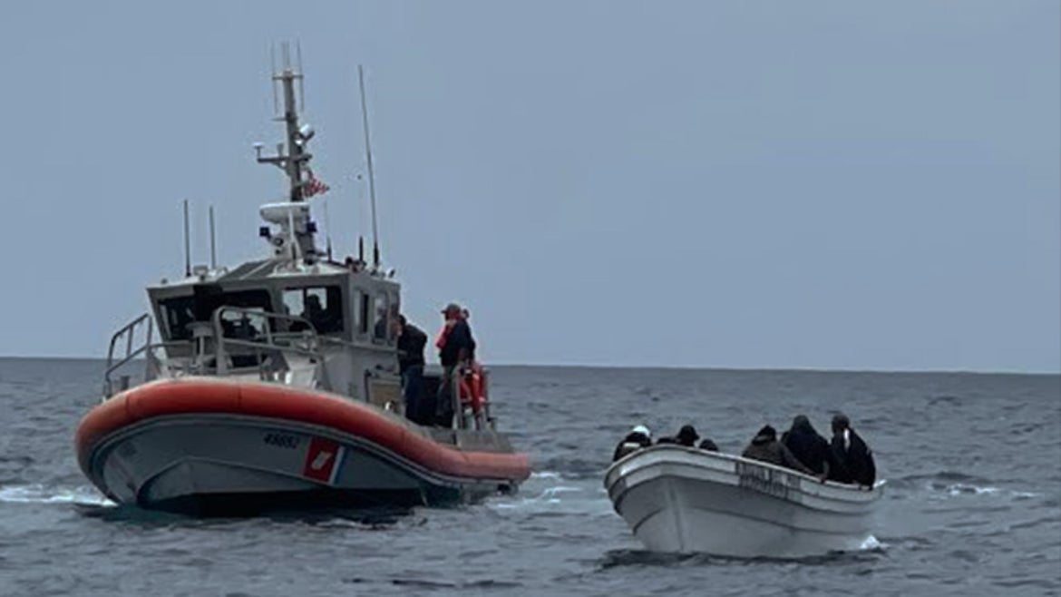 Coast Guard Boat in the water next to vessel the 19 migrants are on