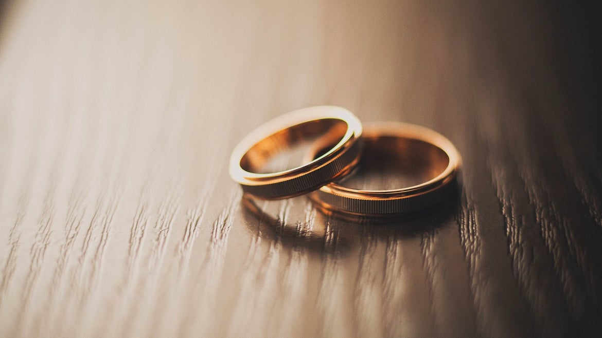 Two gold rings laying on top of each other on a wooden surface