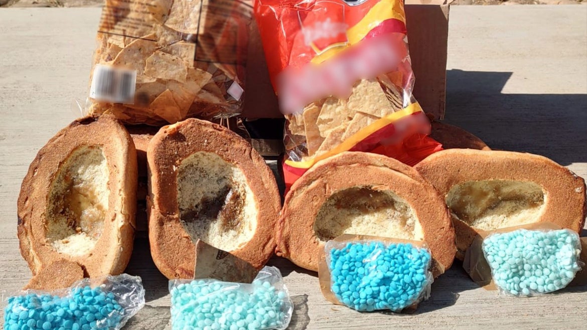 Bread rolls opened to expose rolls of fentanyl pills, sitting in front of corn chip bags also discovered by dog.